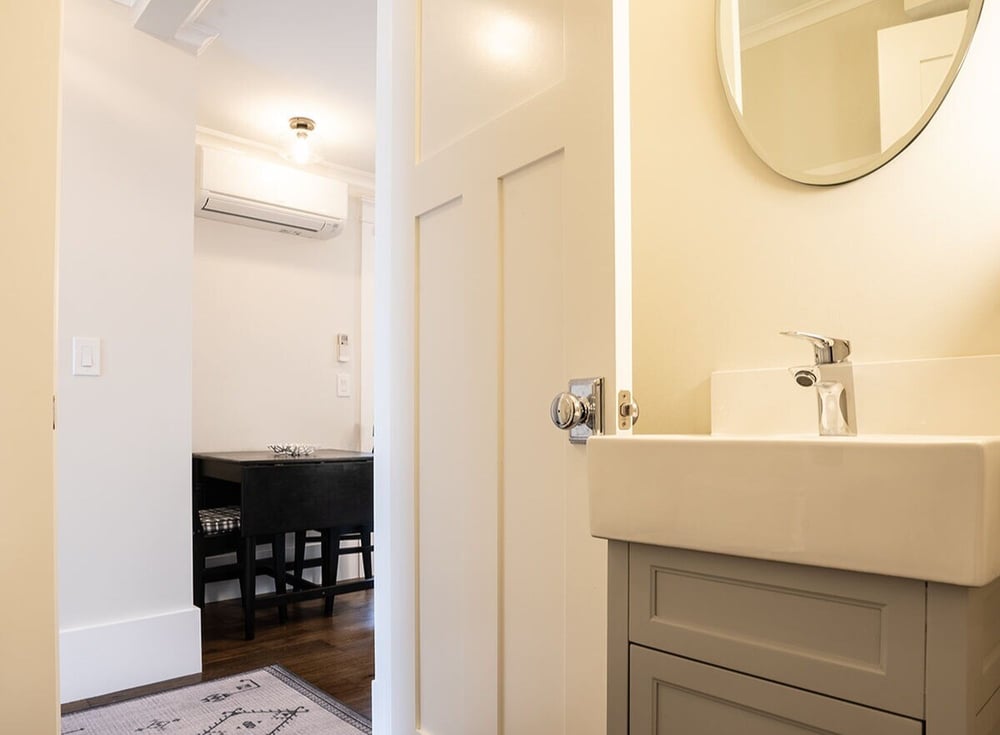 Bathroom-vanity-with-circular-mirror-beneath-light-in-remodel