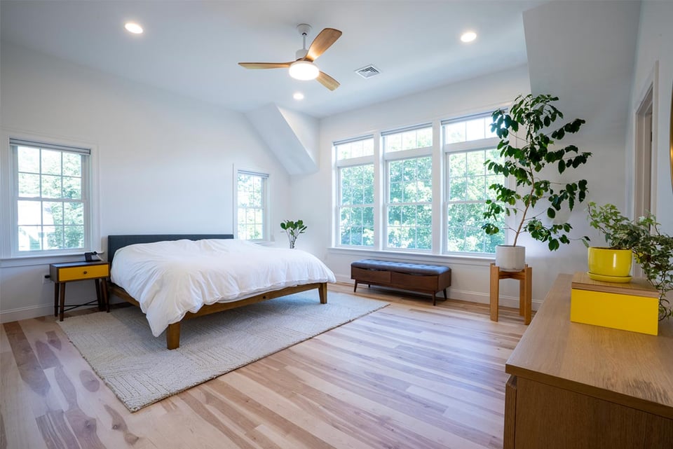 Bright and airy New Hampshire bedroom with natural light, wood floors, and modern decor