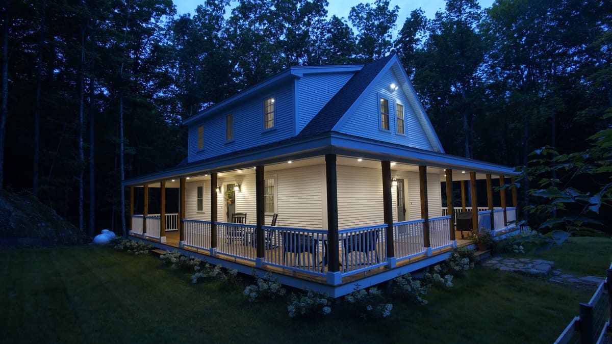 Custom home at twilight with wrap-around porch in Rockingham County, NH