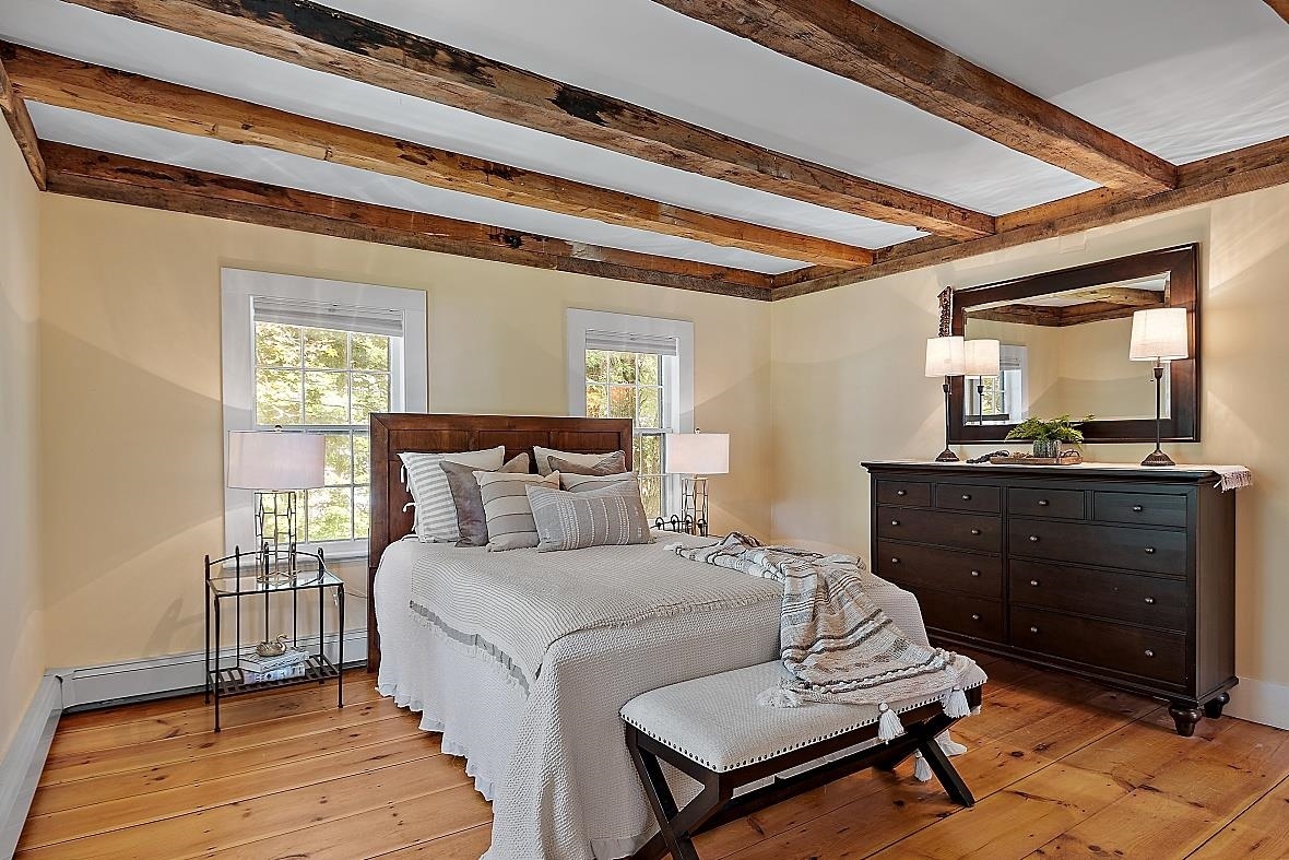 Farmhouse style bedroom renovation in Rockingham County with wood beam ceilings
