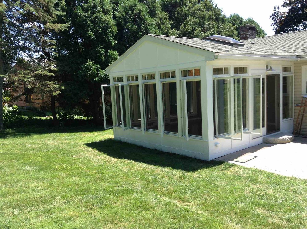 Exterior view of a sunroom addition with open windows, completed by Oxland Builders in New Hampshire