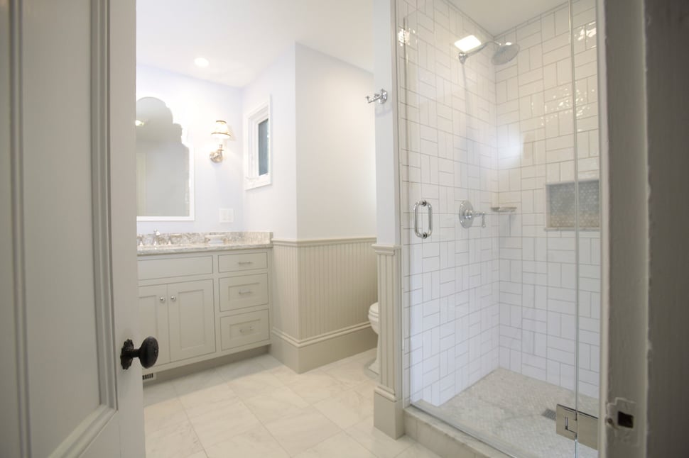 Classic bathroom design with a tiled shower and vintage-inspired decor by Oxland Builders in New Hampshire