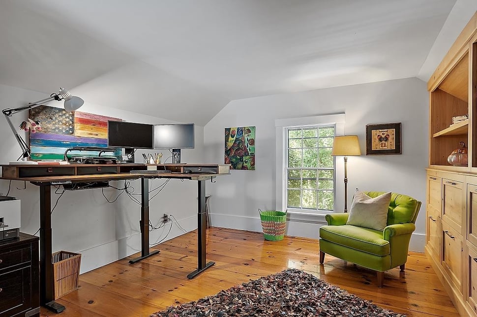 Home office interior with standing desk and chair in front of window by Oxland Builders