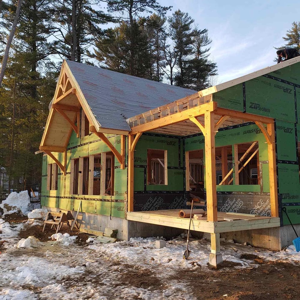 New custom home exterior construction progress with framing and wrapping