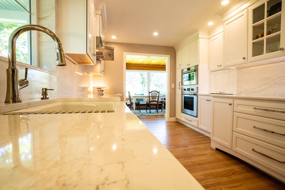 Bright kitchen with marble counters and modern fixtures by Oxland Builders in New Hampshire