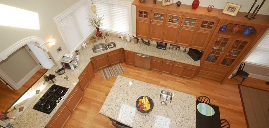 L-Shaped Kitchen With Wood Cabinetry. Kitchen Island in Center of Layout 